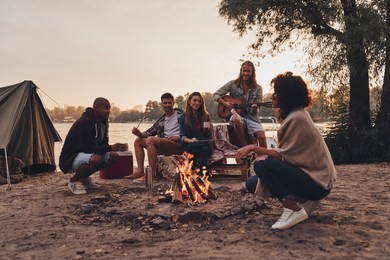 enjoying happy moments. group of young people in casual wear smiling while enjoying beach party near the campfire