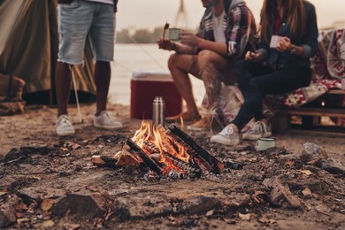 great warm evening. close up of young people eating roasted marshmallows while camping near the lake