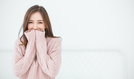 portrait of young beautiful asian woman relax in bedroom. smile happy asian girl hands cover face wear winter cloth. beauty treatment perfect clear skin japanese makeup concept panoramic banner