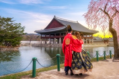 korean lover dressed hanbok traditional of spring cherry blossom in gyeongbokgung palace in seoul, with the name of the palace 'gyeongbokgung' on a sign south korea.