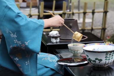 japanese woman in traditional kimono preparing japanese green tea ceremony at garden