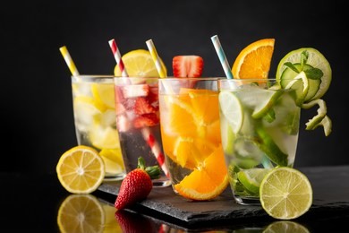 glasses of infused water with fresh strawberries, lime, cucumber and mint leaves, lemon and orange on a black stone tray. focus on the lime glass