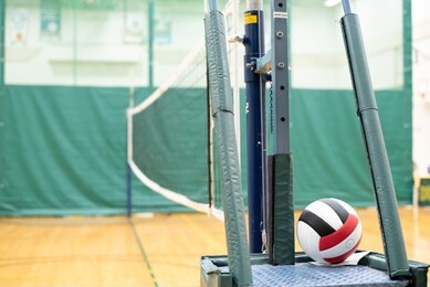 red, black, and white volleyball and net in a school gymnasium.