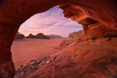 view from natural cave to pink sky in sunset in desert