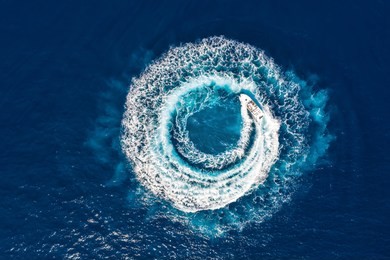 motorboat forms a circle of waves and bubbles with its engines over the blue sea