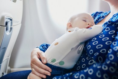 woman with little girl travelling by plane. mother holding her sleeping baby during the flight. travelling with kids