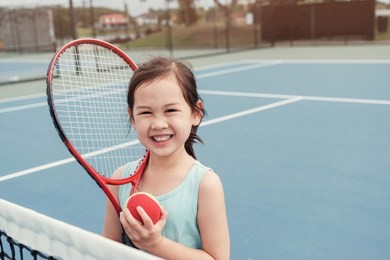 young asian girl tennis player on outdoor blue court