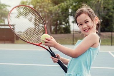young asian girl tennis player on outdoor blue court