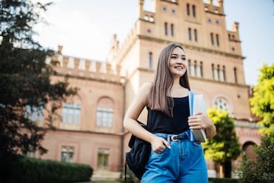 a cute young asian woman walking to class on college campus
