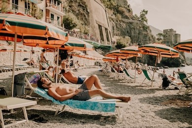 monterosso man on beach bed vintage colors, chairs and umbrellas fill the spiaggia di fegina beach , the wide sandy beach village of monterosso italy, part of the cinque terre italy