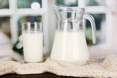 pitcher and glass of milk on crewnecks knitwear on wooden table on window background