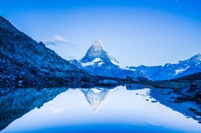 matterhorn mountain as seen before sunrise on a cold summer morning in the alpine region of zermatt in switzerland, captured with its reflection in the riffelsee lake.