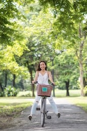 asian beautiful funny  woman legs up riding bicycle at park with sunlight and foliage bokeh background in summer. people healthy and sport lifestyle concept.