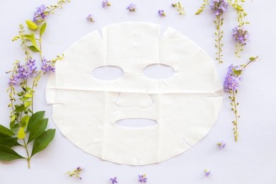 natural sheet mask for health care skin face from herbal flowers on background white