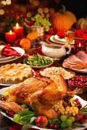 thanksgiving dinner. roasted turkey garnished with cranberries on a rustic style table decoraded with pumpkins, vegetables, pie, flowers and candles