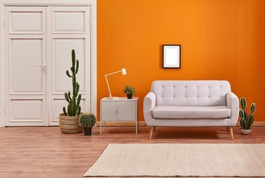 orange living room and orange wall background light grey sofa and avangard white door. modern home decoration brown parquet and carpet design.