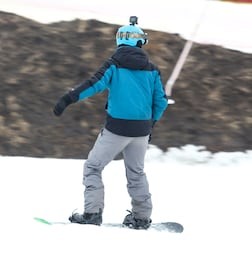 a guy is riding a snowboard from a mountain in winter