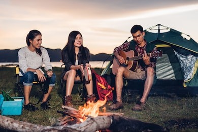 camping tent camp in nature happy friends group night party bonfire and playing guitar together in summer at nature forest