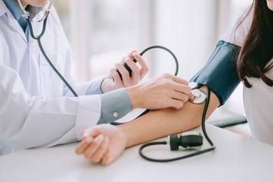 doctor using sphygmomanometer with stethoscope checking blood pressure to a patient in the hospital.