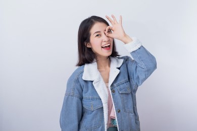 caucasian smiling woman showing her hand with ok sign,  positive happy young asian girl wearing blue casual clothes portrait in studio