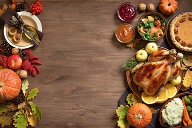 thanksgiving dinner background with turkey and all sides dishes, pumpkin pie, fall leaves and seasonal autumnal decor on wooden background, top view, copy space.