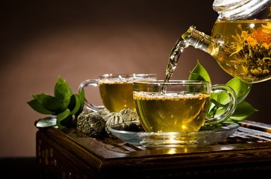 horizontal photo, of the glass teapot flow green tea in cup on brown background,  tea ceremony