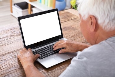 senior man using laptop with blank white screen