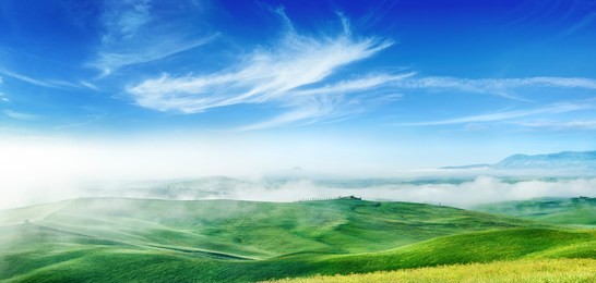 panorama, italian beautiful landscape, foggy rolling fields of tuscany in light of the rising sun