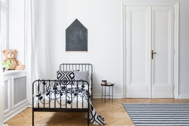 black and white bed in teenager's bedroom interior with plush toy and poster on the wall. real photo