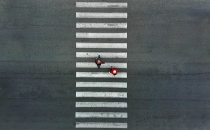 aerial. two pedestrians walk on a pedestrian crossing.