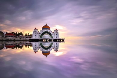 beautiful reflections during sunrise over malacca straits mosque (masjid selat melaka), a mosque located on malacca island near malacca town in malacca state, malaysia.
