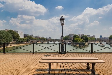 the wooden bench on pont des arts bridge in paris with view of pont neuf and cite island in the middle of seine river