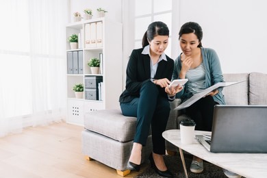 insurance agent and the young girl discussing the insurance plan and counting on calculator. bright home office lifestyle. female agent consulting clients in living room.