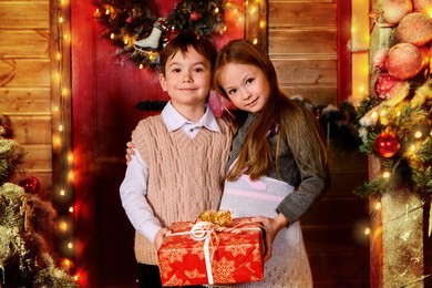 pretty children stand on the porch of a house decorated for christmas with gift box. time for miracles. 