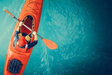 kayaker lake tour aerial photo. red kayak and caucasian paddling sportsman in his 30s.