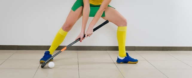  beautiful young woman holding hockey stick and ball against white background