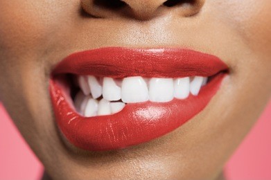 close-up view of an female biting her red lip over colored background