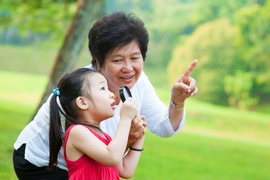 asian grandmother and granddaughter exploring nature by magnifier