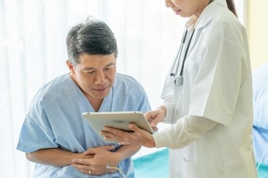 asian senior patient on hospital bed discussing with female doctor - selective focus point