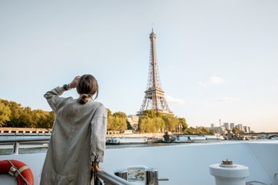 young woman enjoying beautiful landscape view on the riverside with eiffel tower from the boat during the sunset in paris