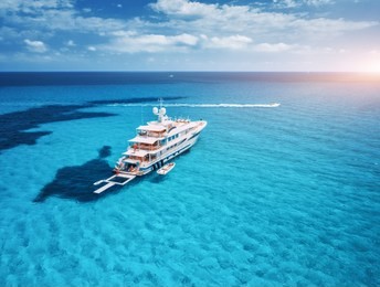 yacht on the azure seashore in balearic islands. aerial view of floating boat with people in transparent sea at sunset in summer. top view from drone. seascape with luxury yachts in bay. travel