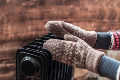 women's hands in christmas, warm, winter mittens on the heater. keep warm in the winter, cold evenings. heating season
