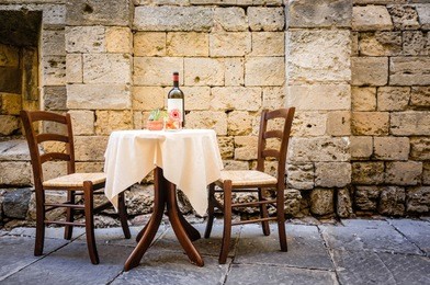 table and chairs in front of historic wall - tuscany/italy