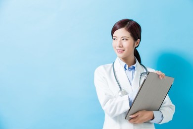 woman doctor look somewhere and take tablet pc on the blue background