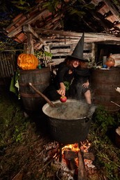 witch boiling spells in a cast iron black pot in her shed