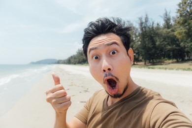 wow and surprised face of asian man selfie himself on the beach of thailand.