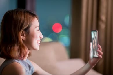 woman sit on sofa and chating online with friend at night