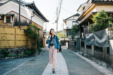 full length photo of an elegant lady walking in the path with japanese traditional building around. cheerful tourist travel in fun summer in japan. japanese lady going home.