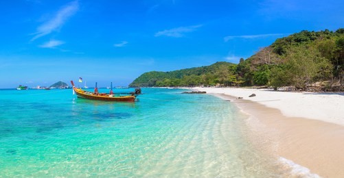 panorama of traditional long tail boat on coral (ko he) island near phuket island, thailand in a summer day