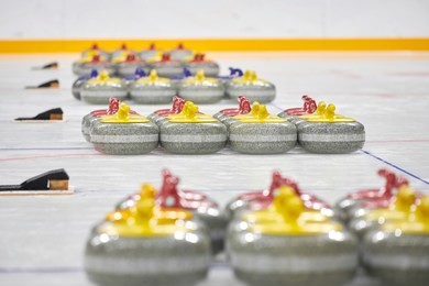 curling stones equipment on the ice. group of  yellow and red  curling rocks in the rings on ice with bright background. curling - closeup of rocks. granite stones for curling game on the ice. 